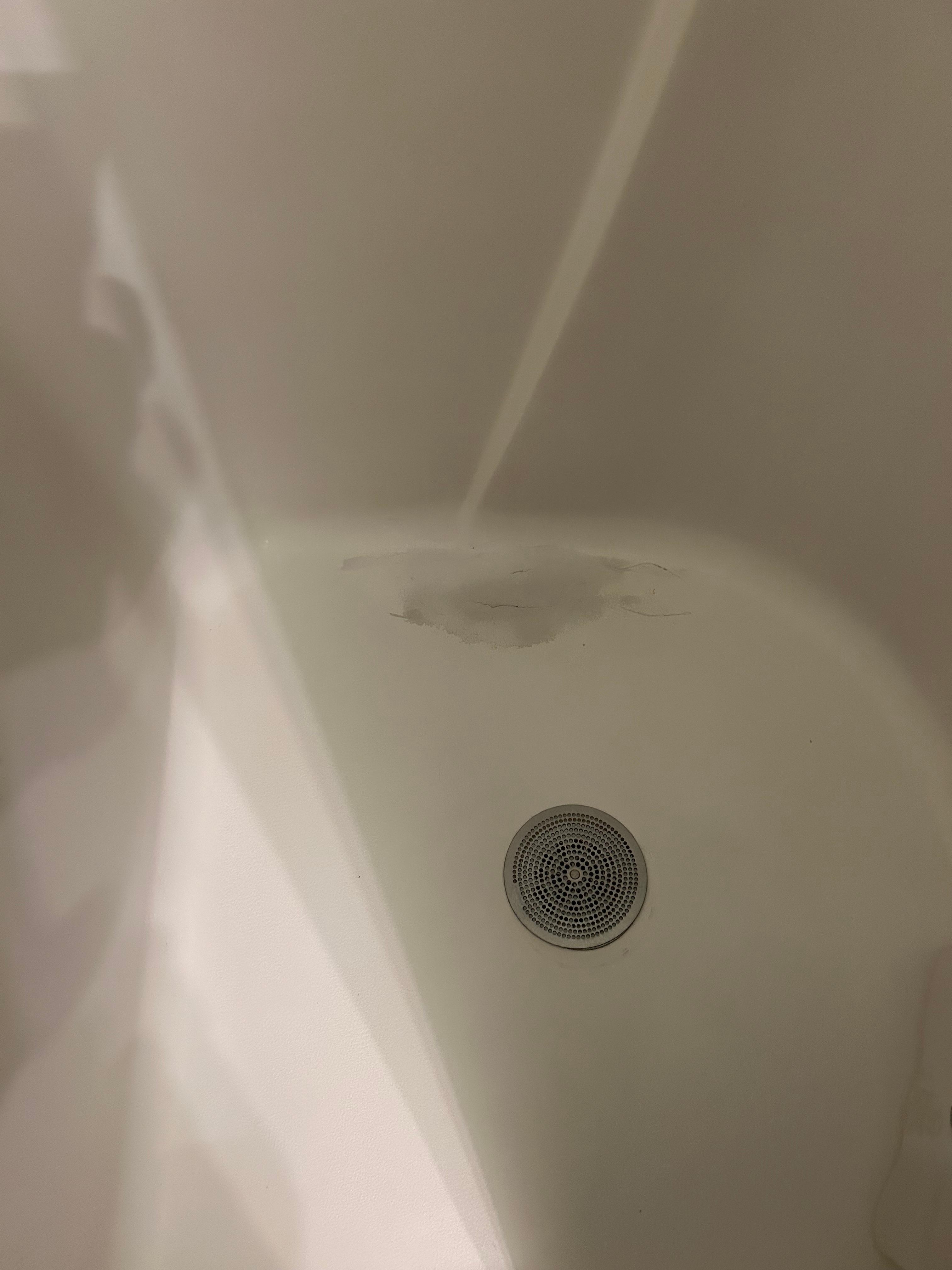 Cracked and patched small shower stall.