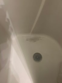 Cracked and patched small shower stall.