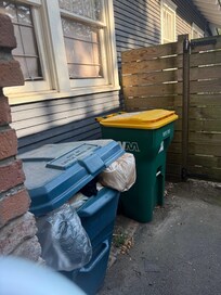 Overflowing trash can by front porch with terrible odor coming from it.