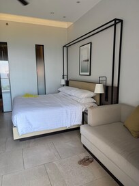 Junior Suite Bed and couch, bathroom is behind tall windows