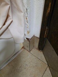 By the back of the tub behind the door