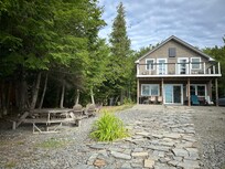 View of the main house from the dock including picnic table and fire pit to the left