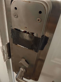 Room side view of door lock covered with duct tape