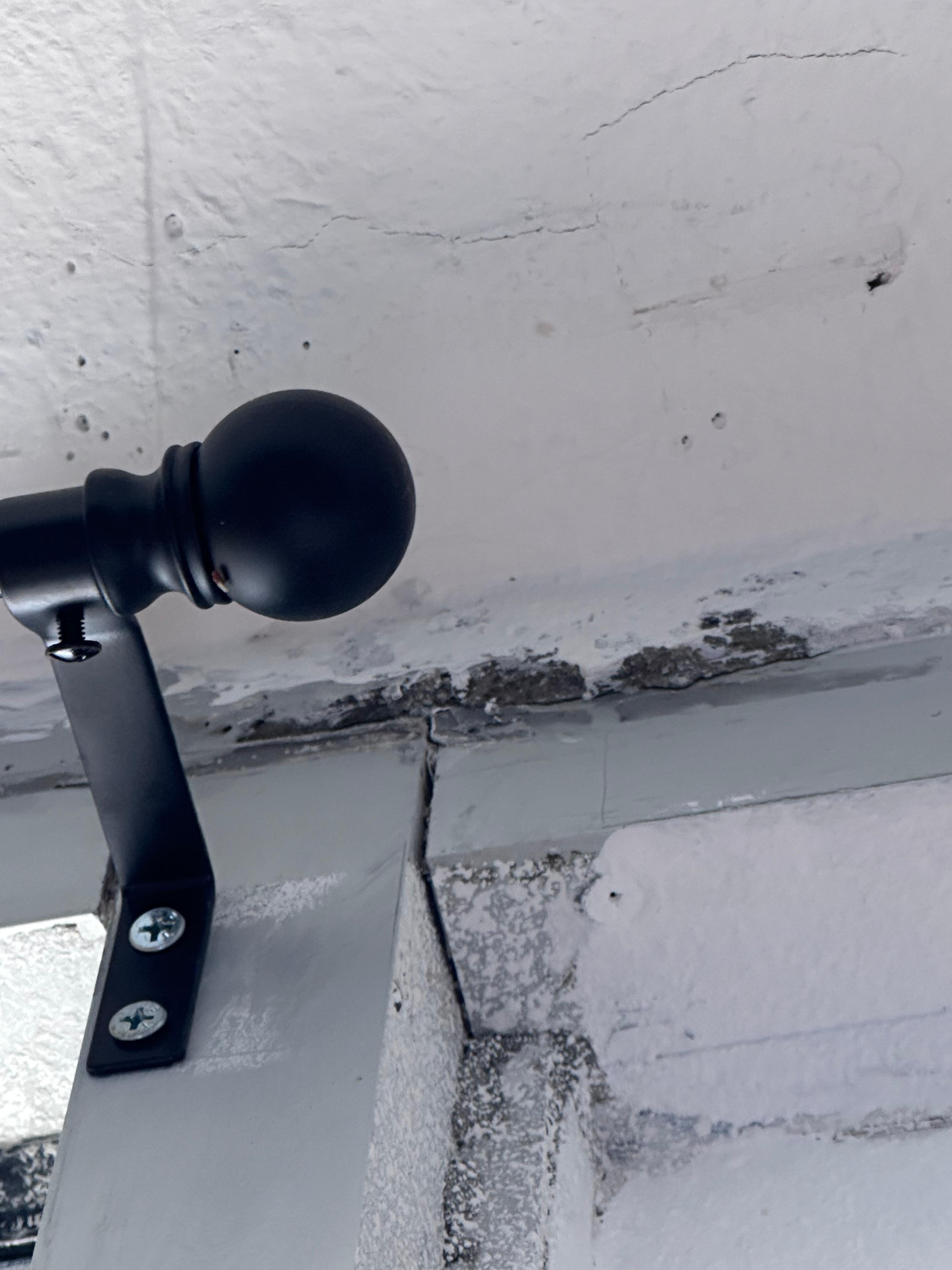 Mold above the curtain rod on the wall 