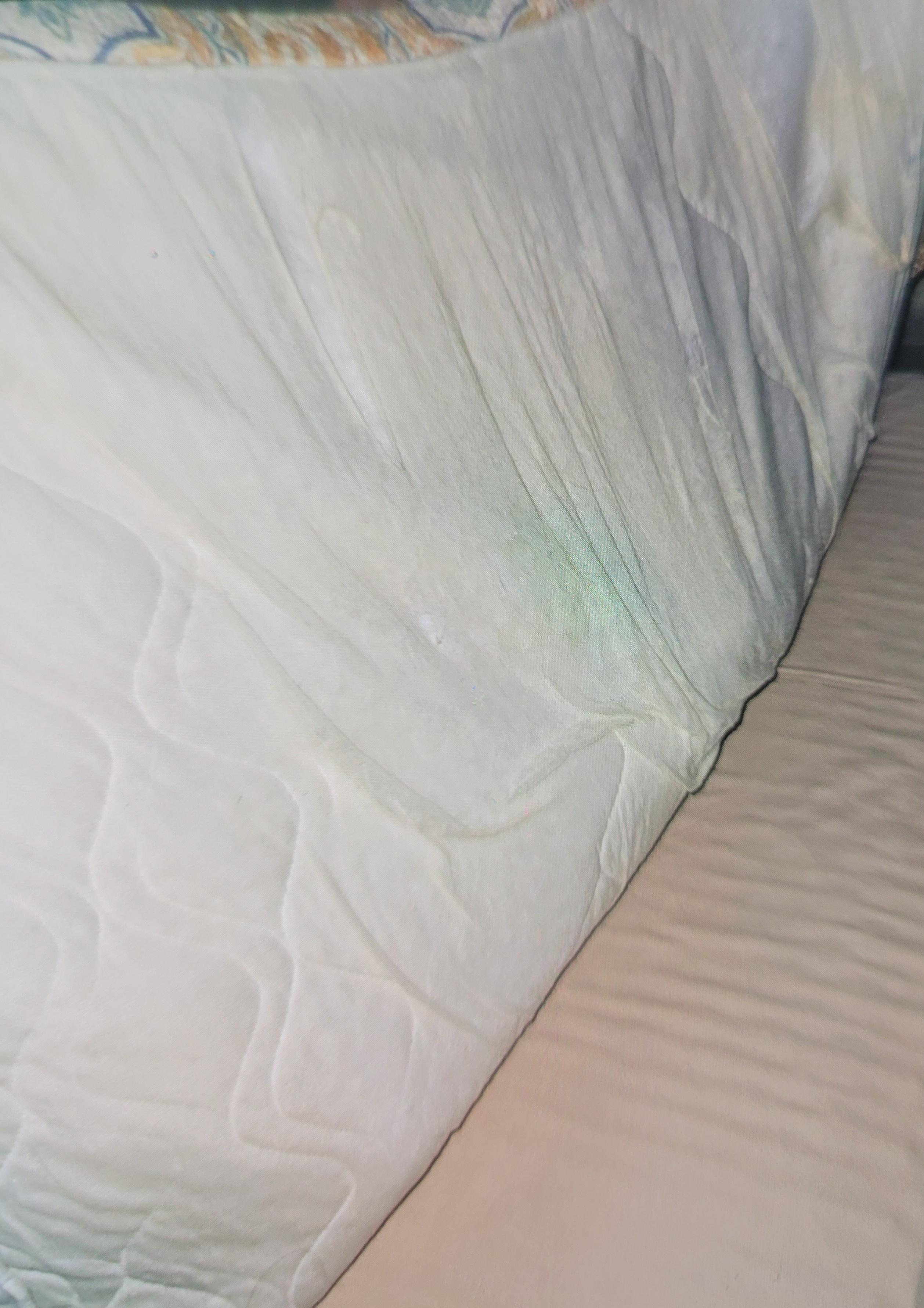 Tattered comforter at the top of bed 1