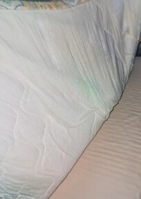 Tattered comforter at the top of bed 1