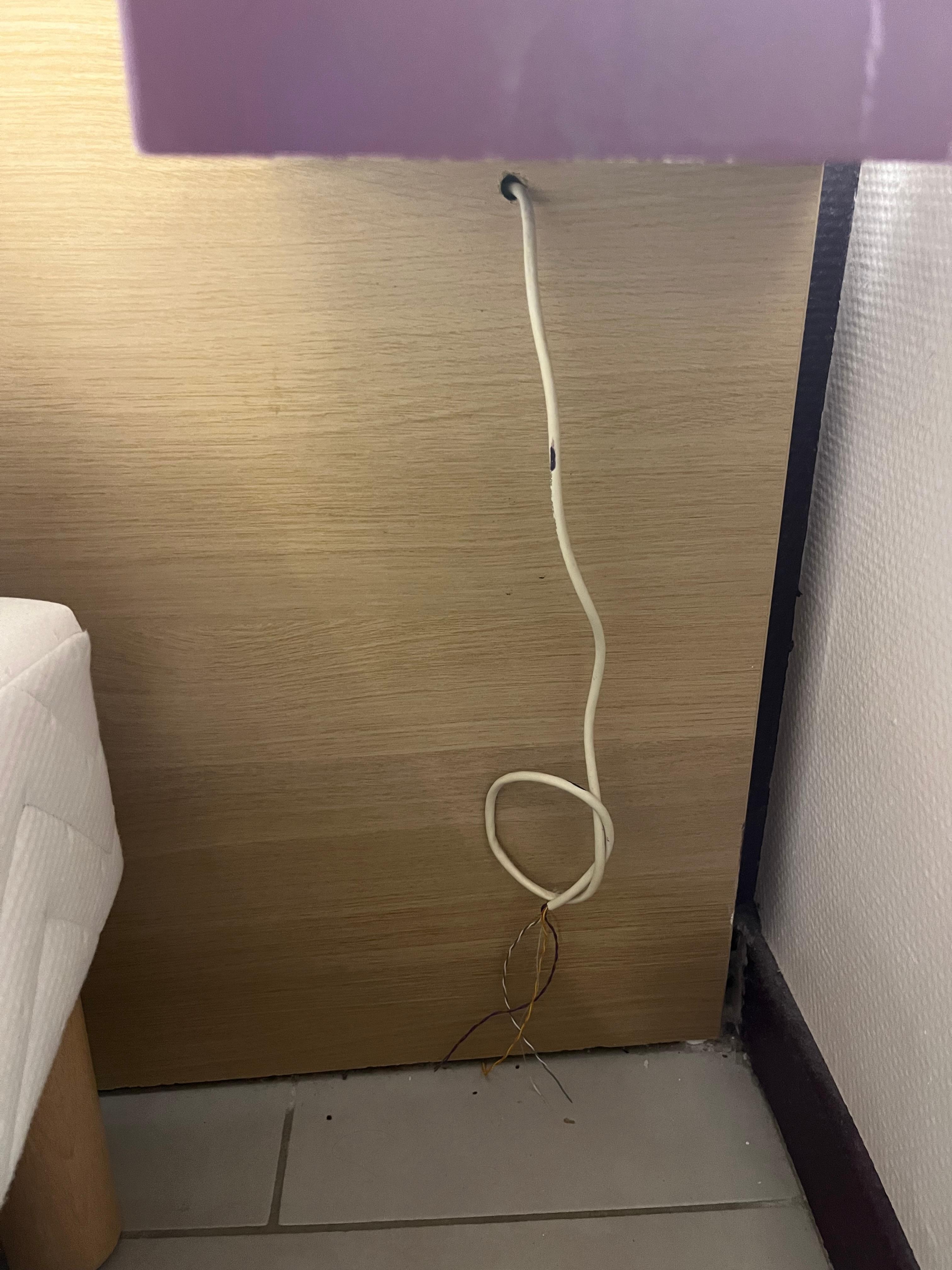 Cables dénudés sous une des tables de chevet