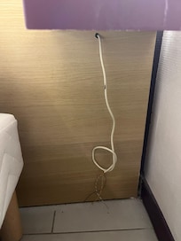 Cables dénudés sous une des tables de chevet