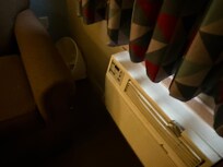 Lampshade shoved in between the wall and couch and duct tape to fix the AC unit on it