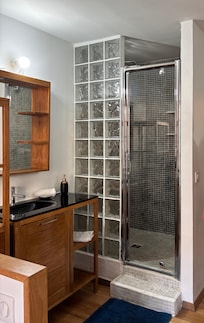 The shower and outside sink, separated from bed by a half wall. The toilet is in a separate WC with a small sink.