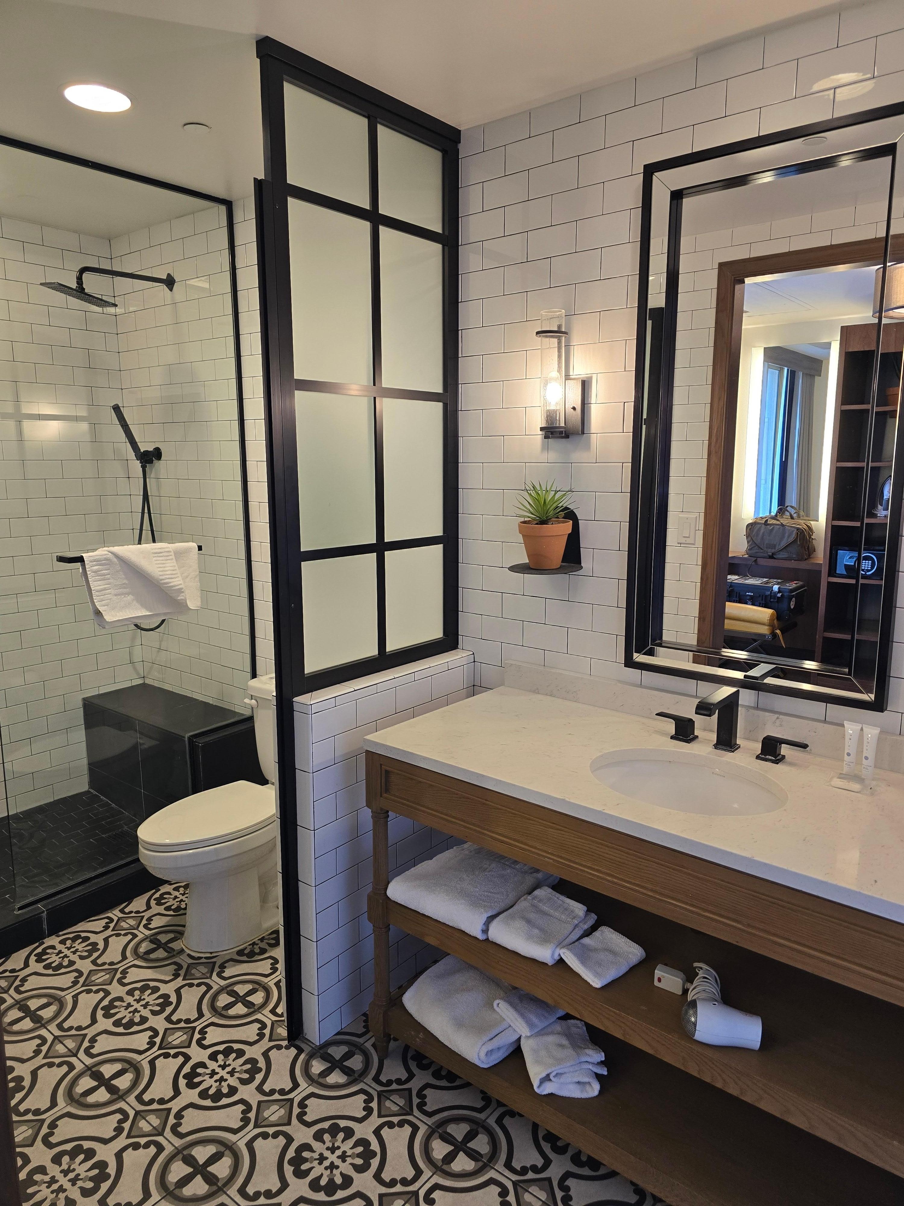 North side (mountain view) of Tower; sink area is open to the room, toilet and shower compartment have a (loud creaking) metal frame door with semi opaque glazing. Shower is half enclosed with glass (water on floor)