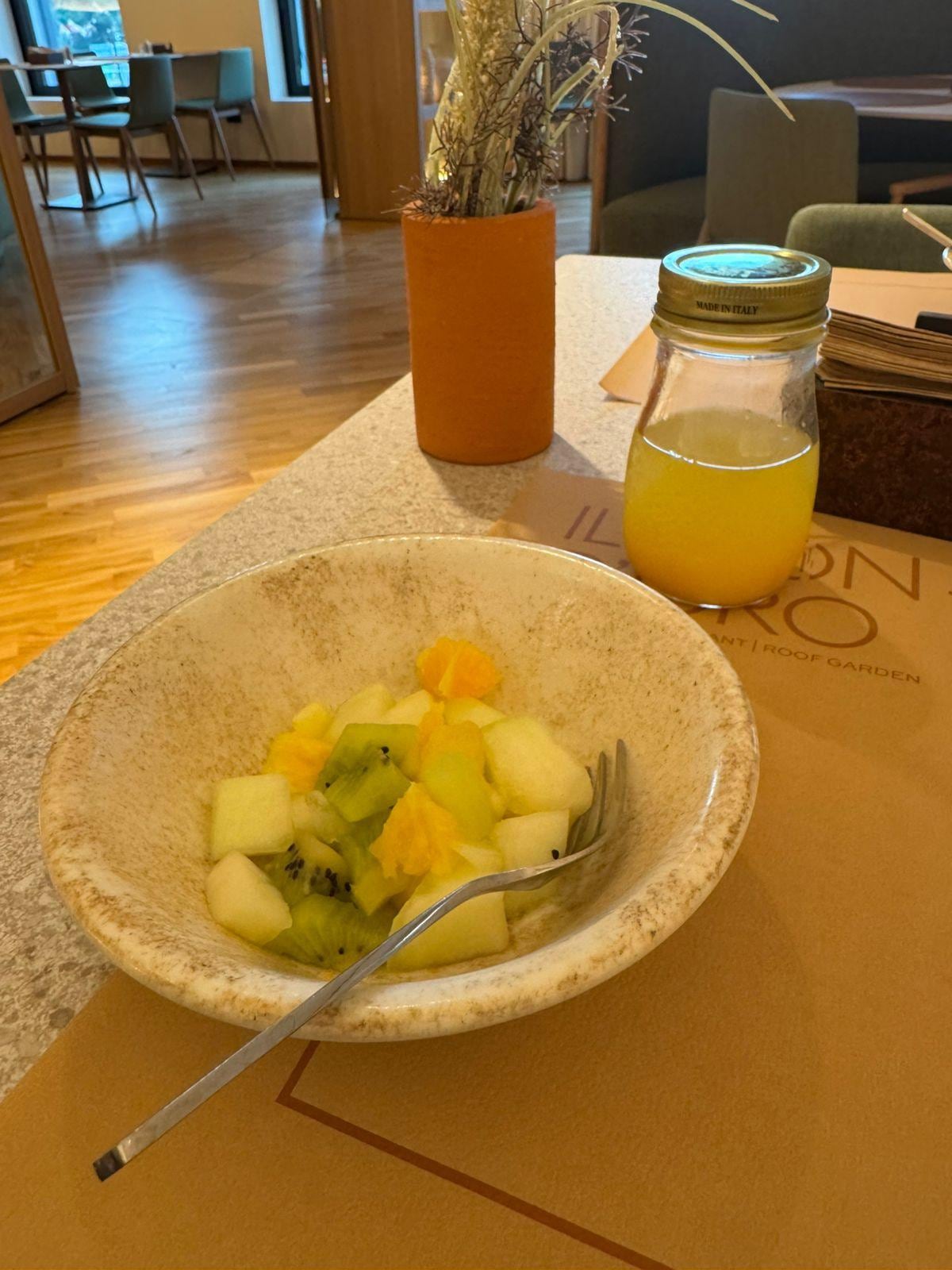 Dois itens fornecidos no café da manhã em porções (salada de frutas e suco de laranja).