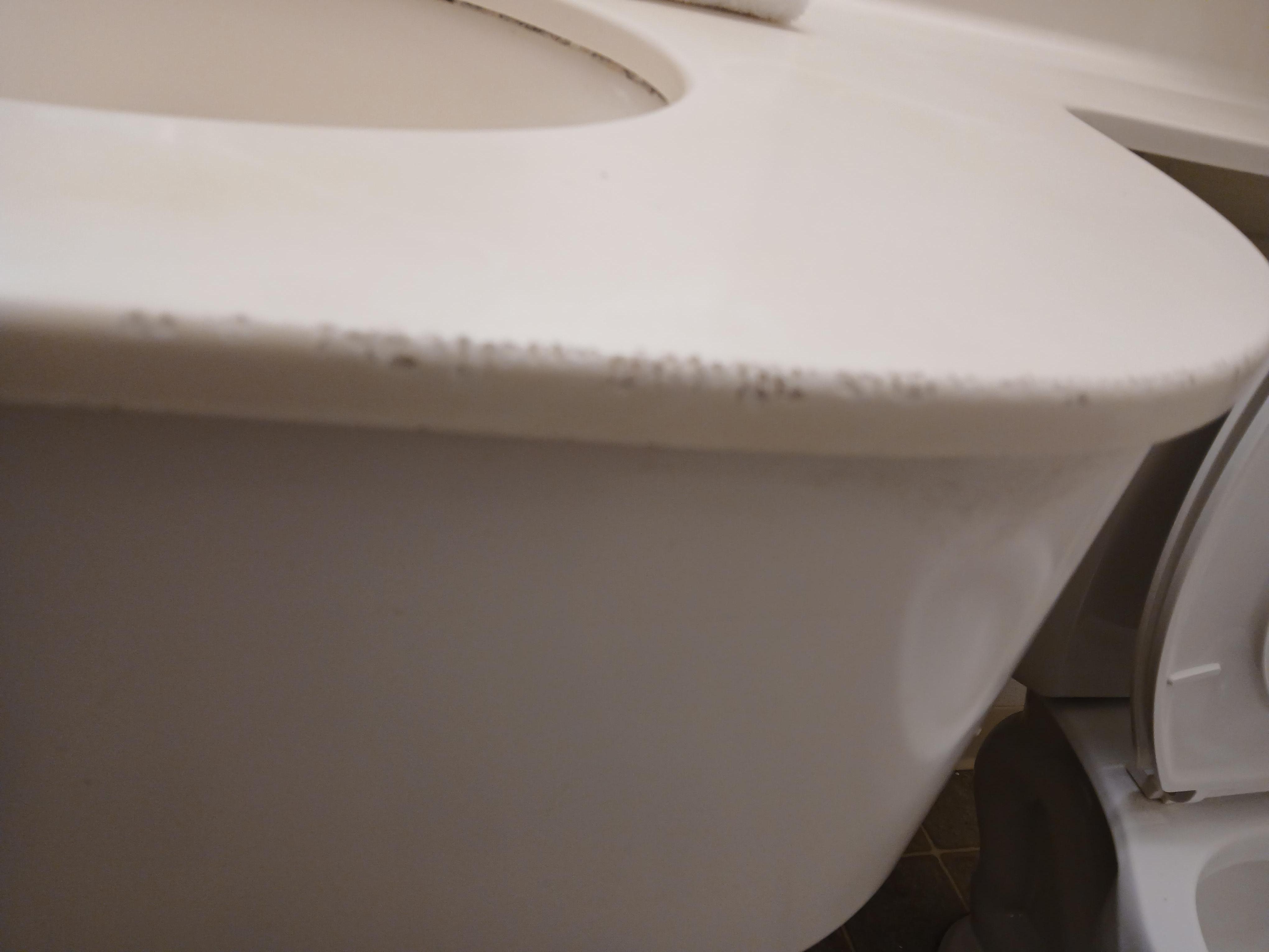 Sink in bathroom gouged and dirty.