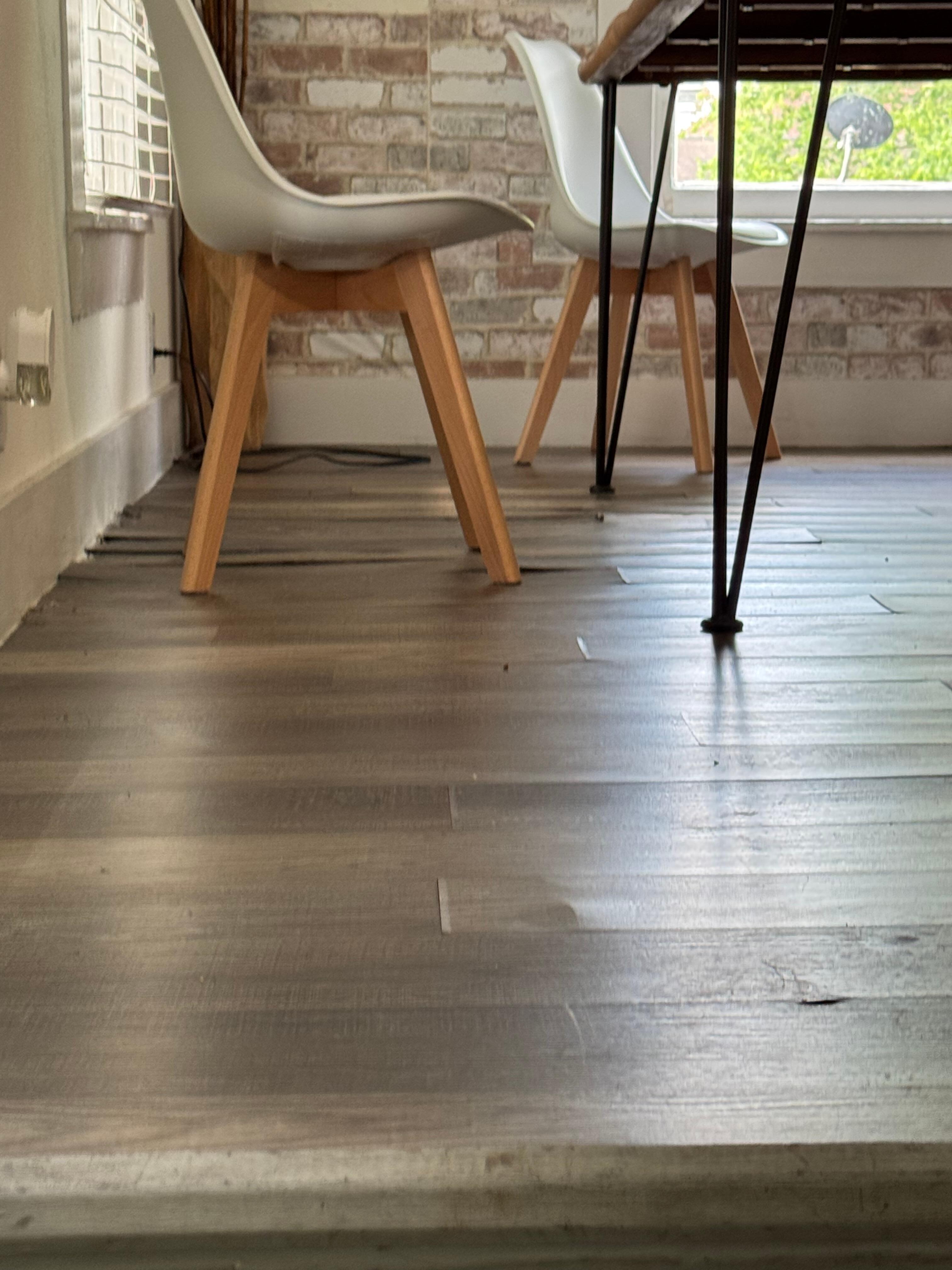 Flooring pulling up is bad under dining table.