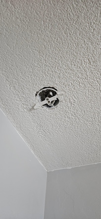 Open faced electrical box with exposed capped wires.