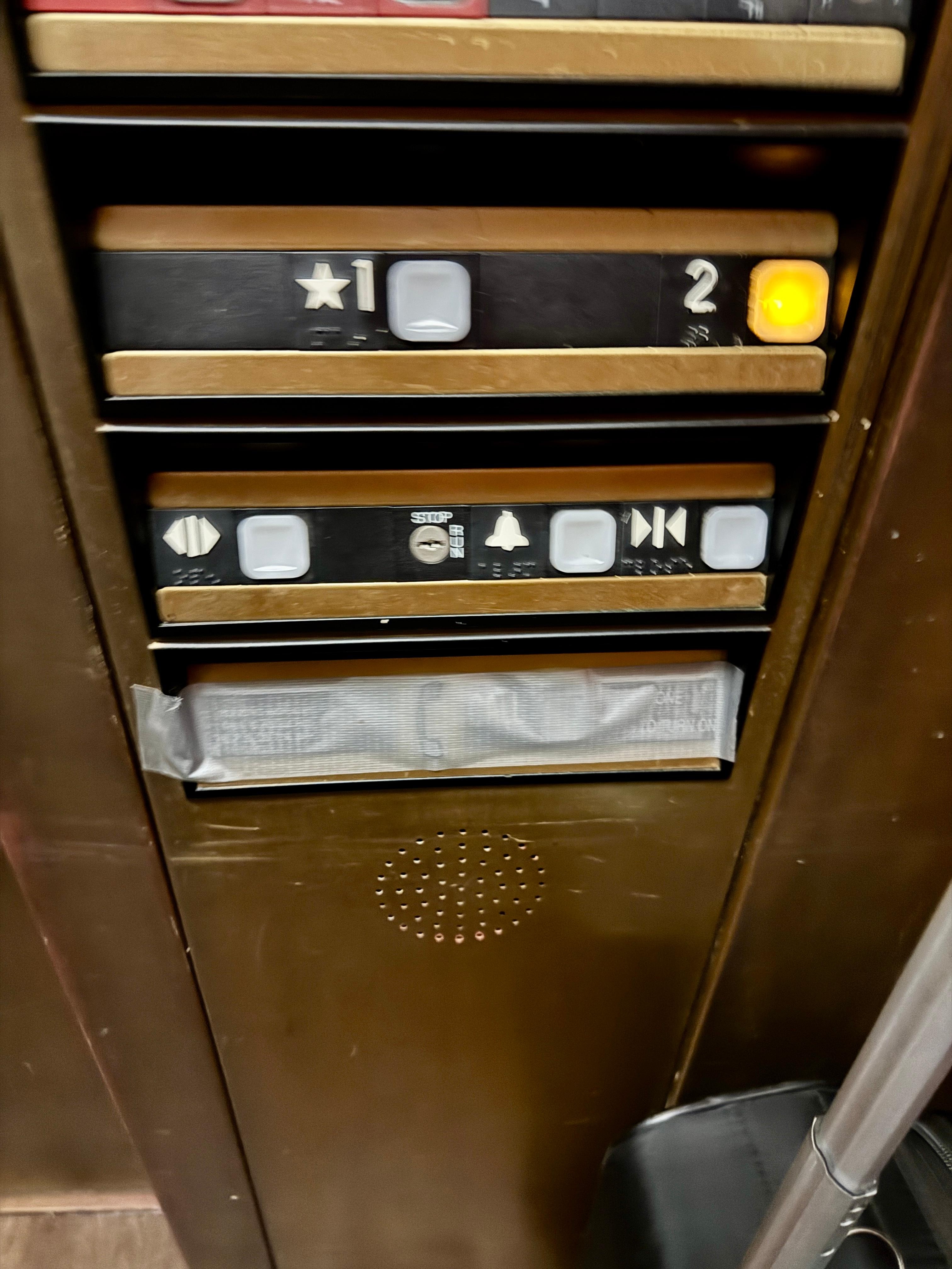 elevator panel with the emergency buttons taped over.