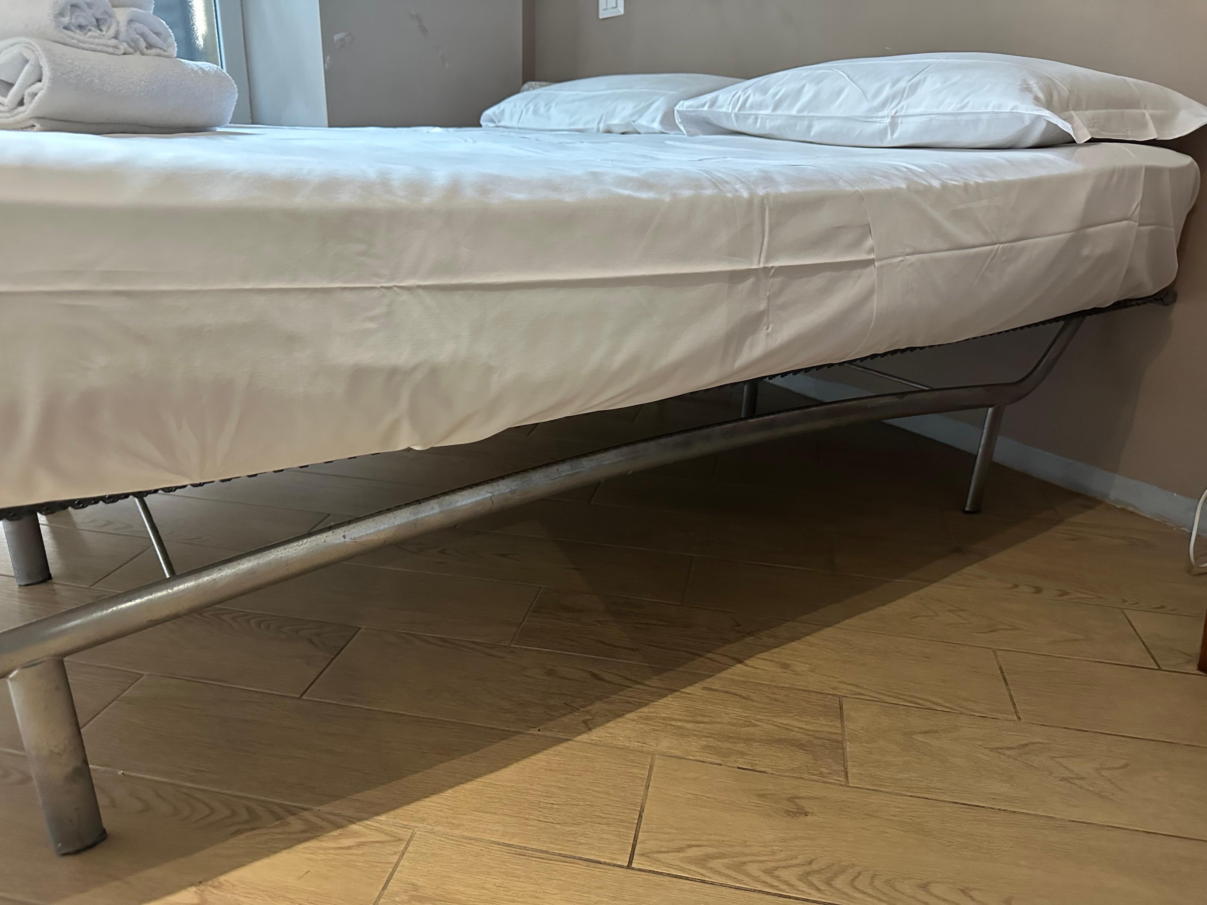 Very thin and soggy mattress without a headboard against dirty wall