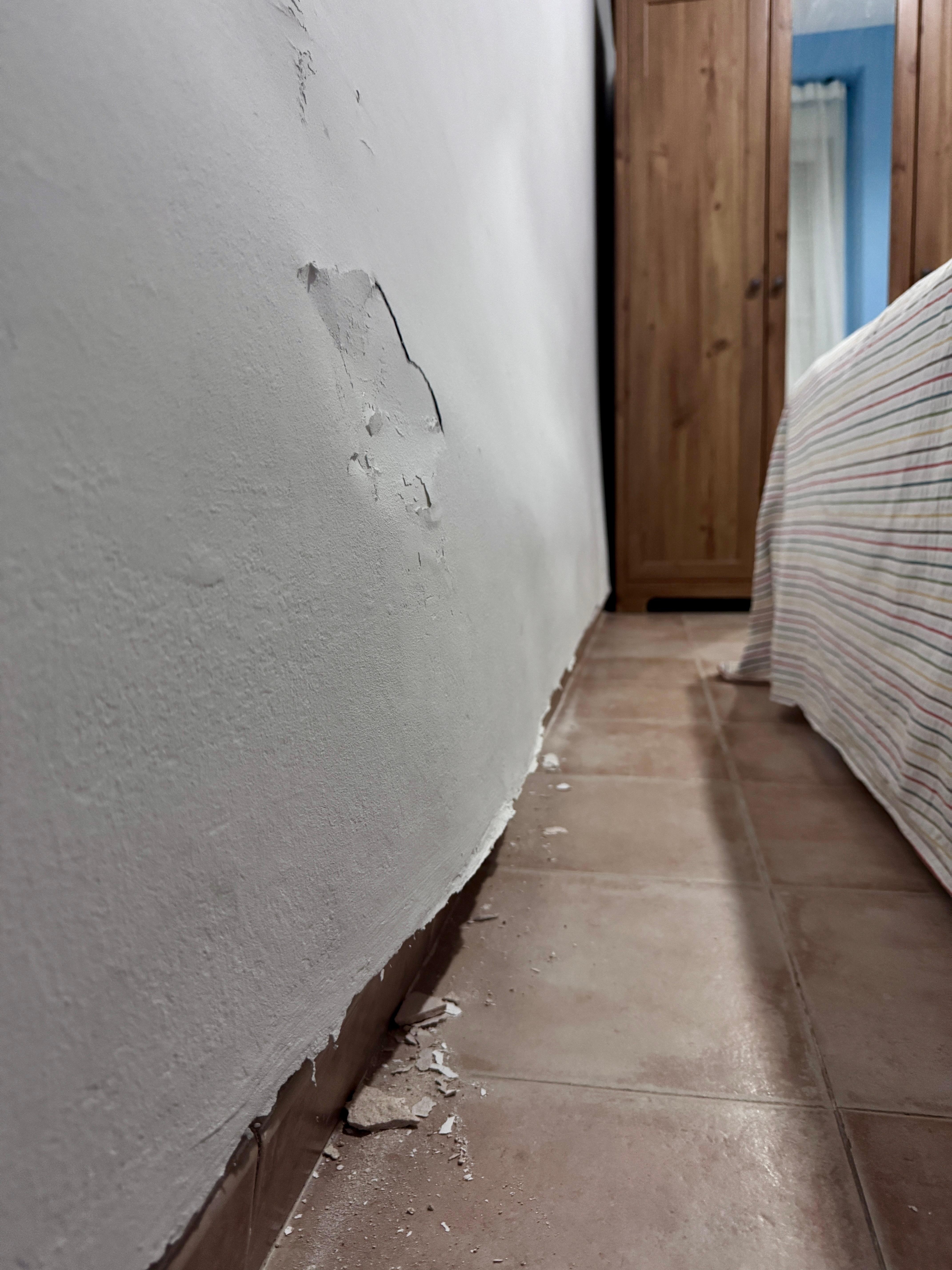 The plaster peeling away from a very swollen, bulging bedroom wall.