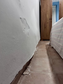 The plaster peeling away from a very swollen, bulging bedroom wall.