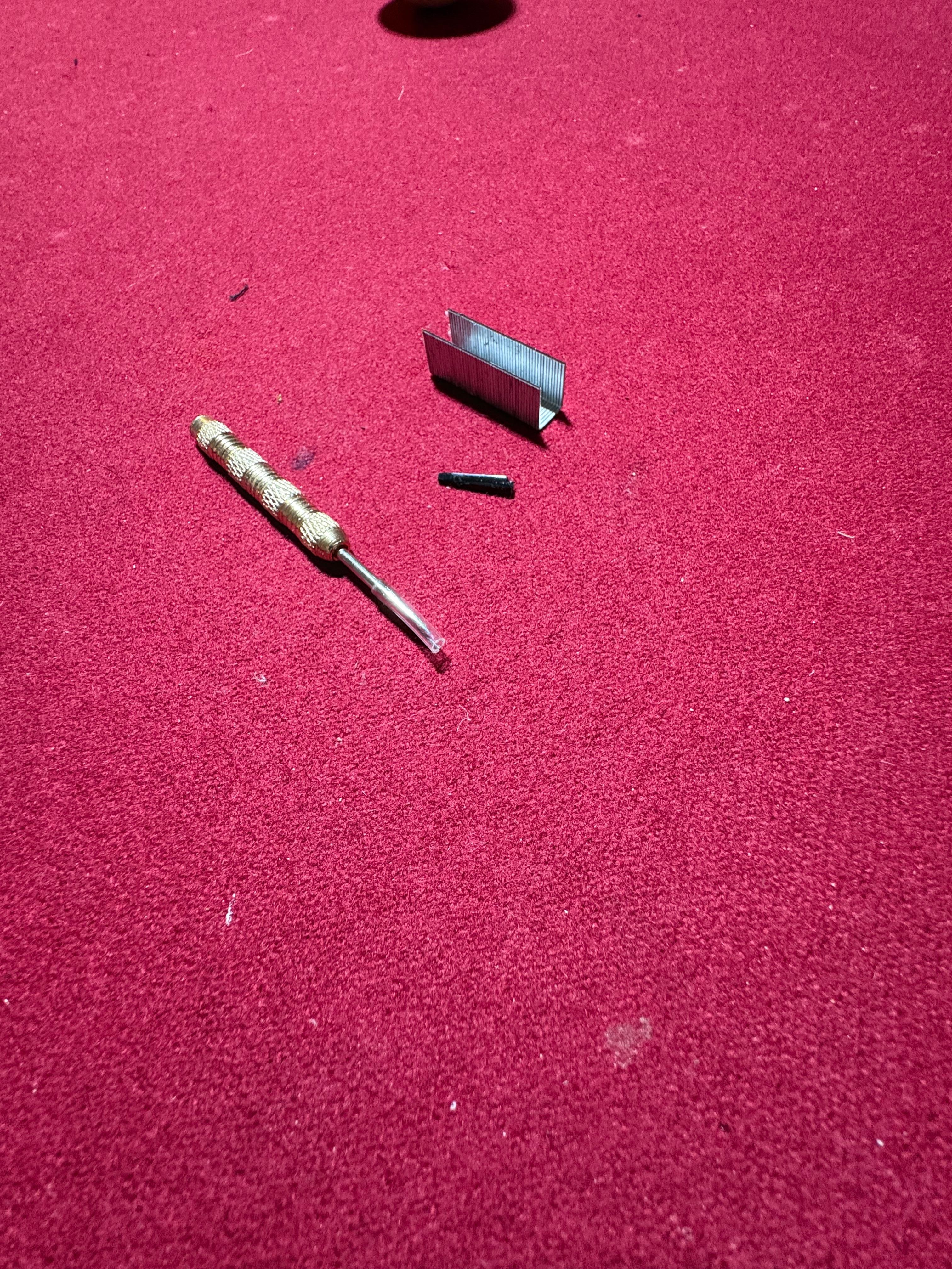 Broken dart lying in the garage gaming floor. 