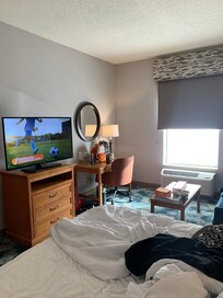 TV with swivel base and amazing picture beside a fridge, microwave and desk.