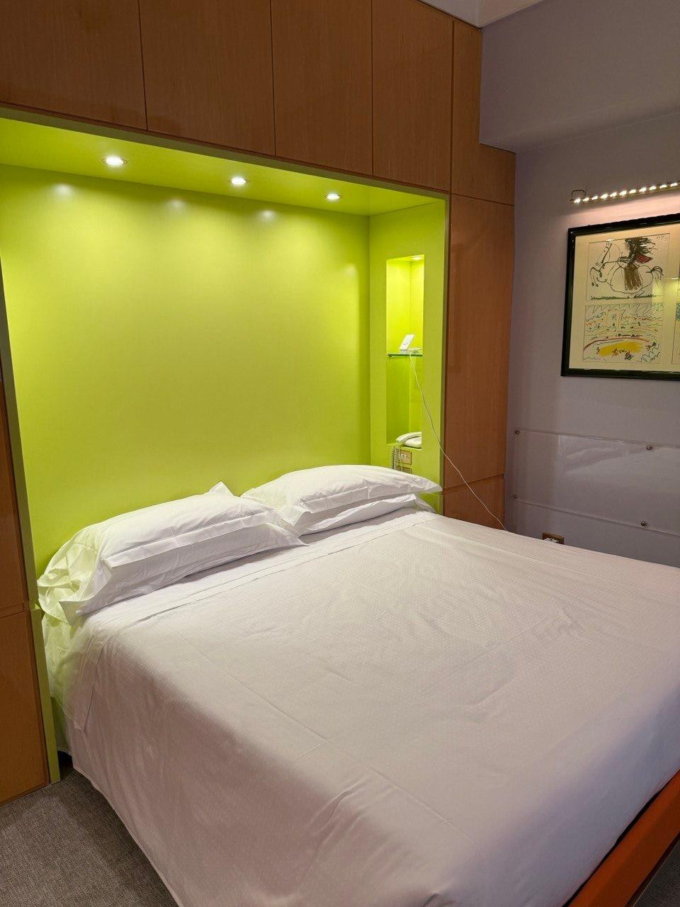 Albani Hotel - Bed with green wall.  There is no plug available on the left side of the bed (can't charge phone).