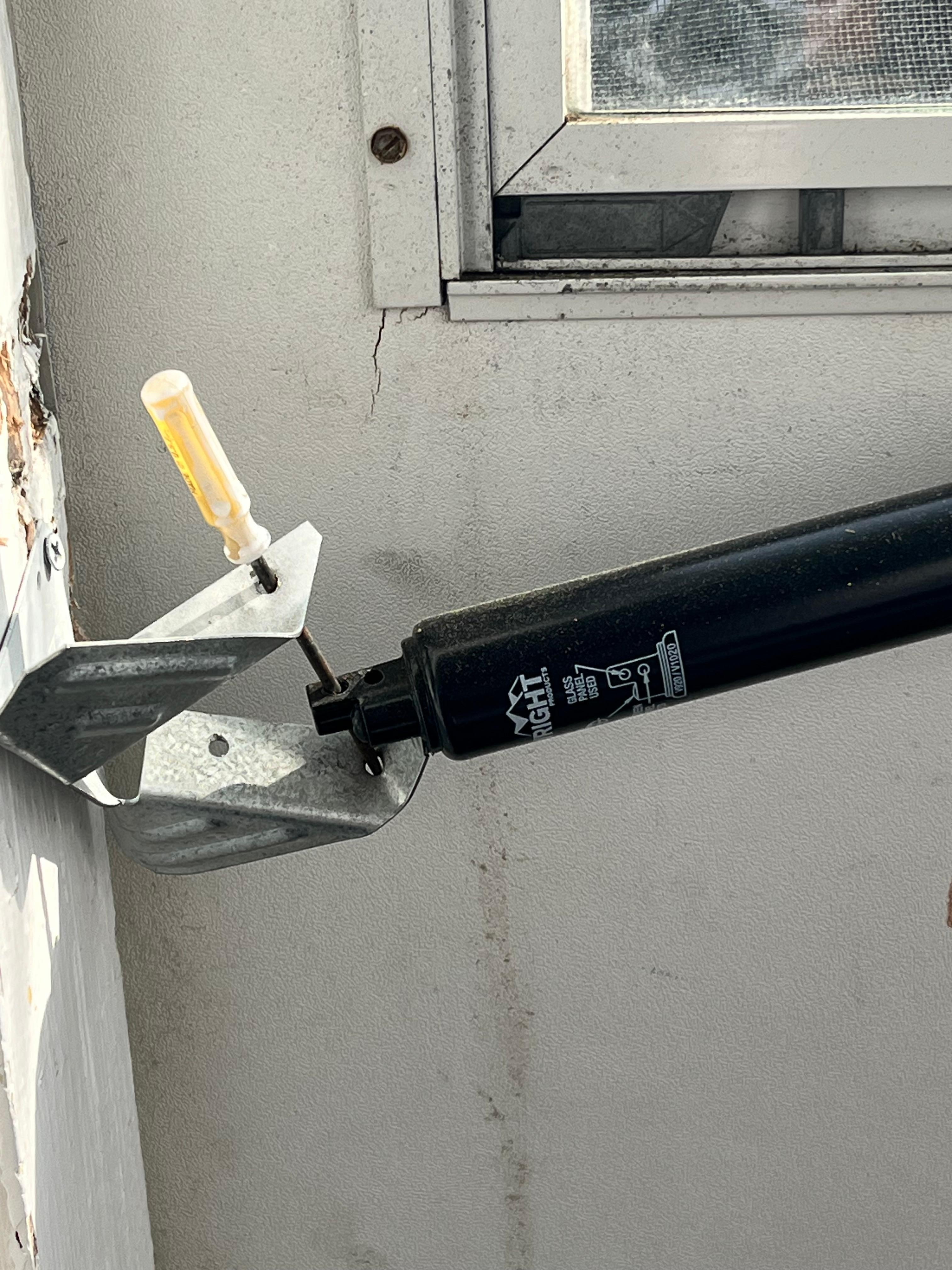 Screen door being held with a mini screw driver. The part is $12 like really?!