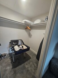 Spacious closet with a few hangers and ample room for a dresser, making clothing storage easier.