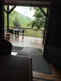 Standing inside next to big dining room table looking outside to front porch and view.