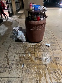 Trash overflowing in front of building.
Stained sidewalk