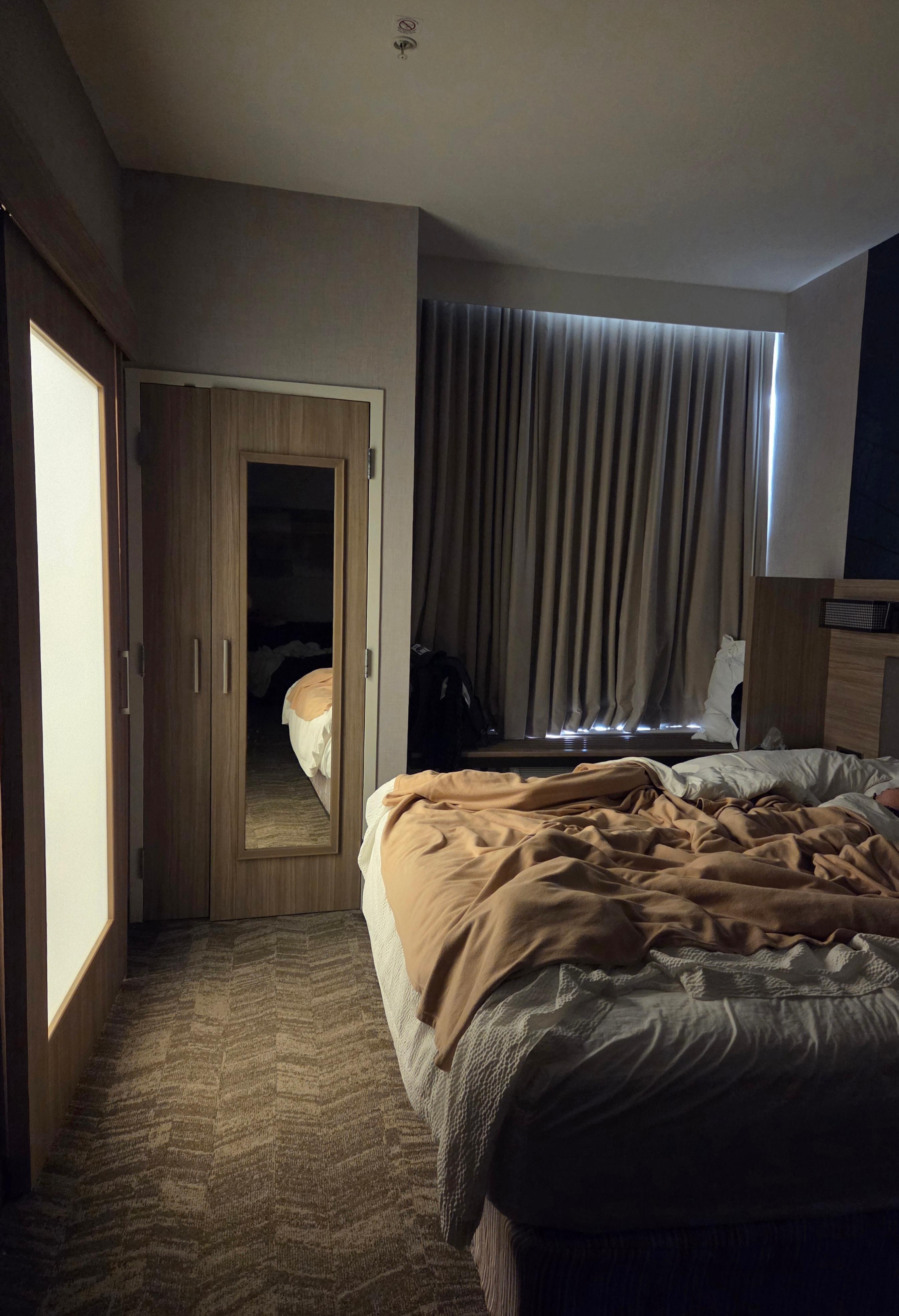 Bathroom light through door panel and bed in front of door.