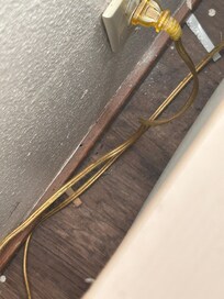 Trash behind a nightstand. Don't know if one item is a cigarette butt?