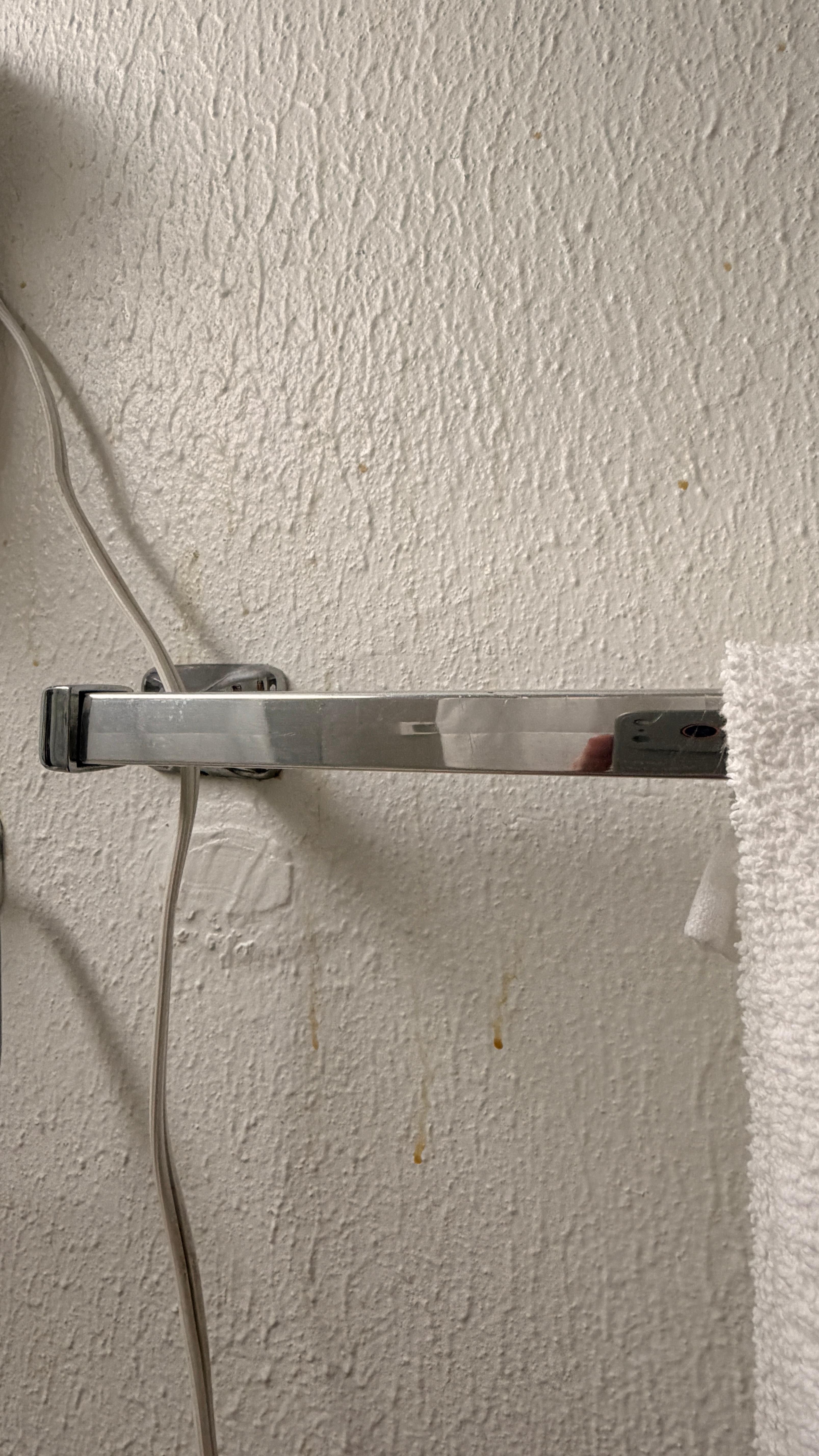 Gunk on bathroom wall near towels. 