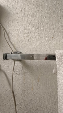 Gunk on bathroom wall near towels.