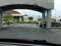View of the office covered parking. Old damage to building and old weathered caution tape. Could not drive through.