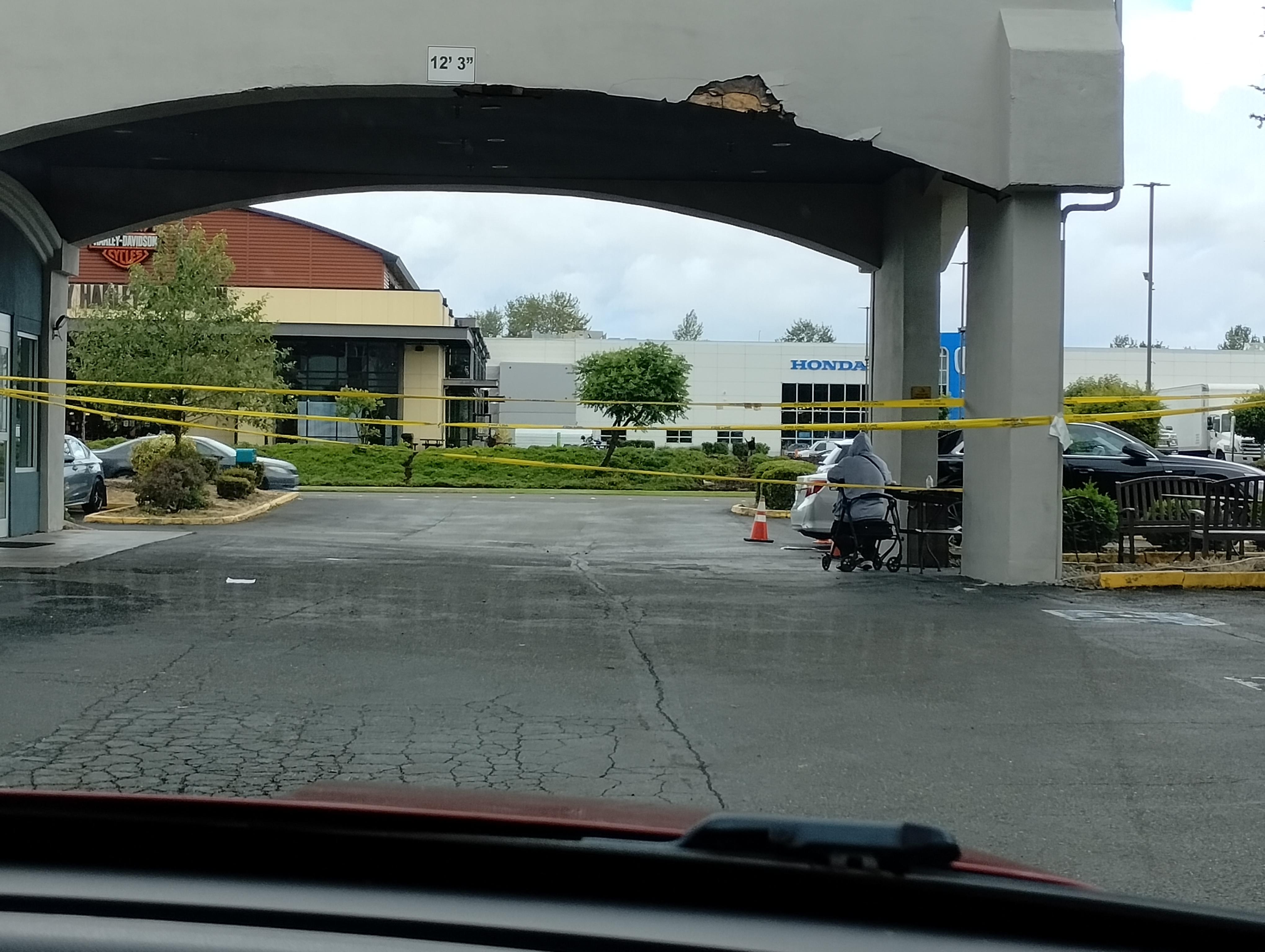 View of the office covered parking. Old damage to building and old weathered caution tape. Could not drive through.