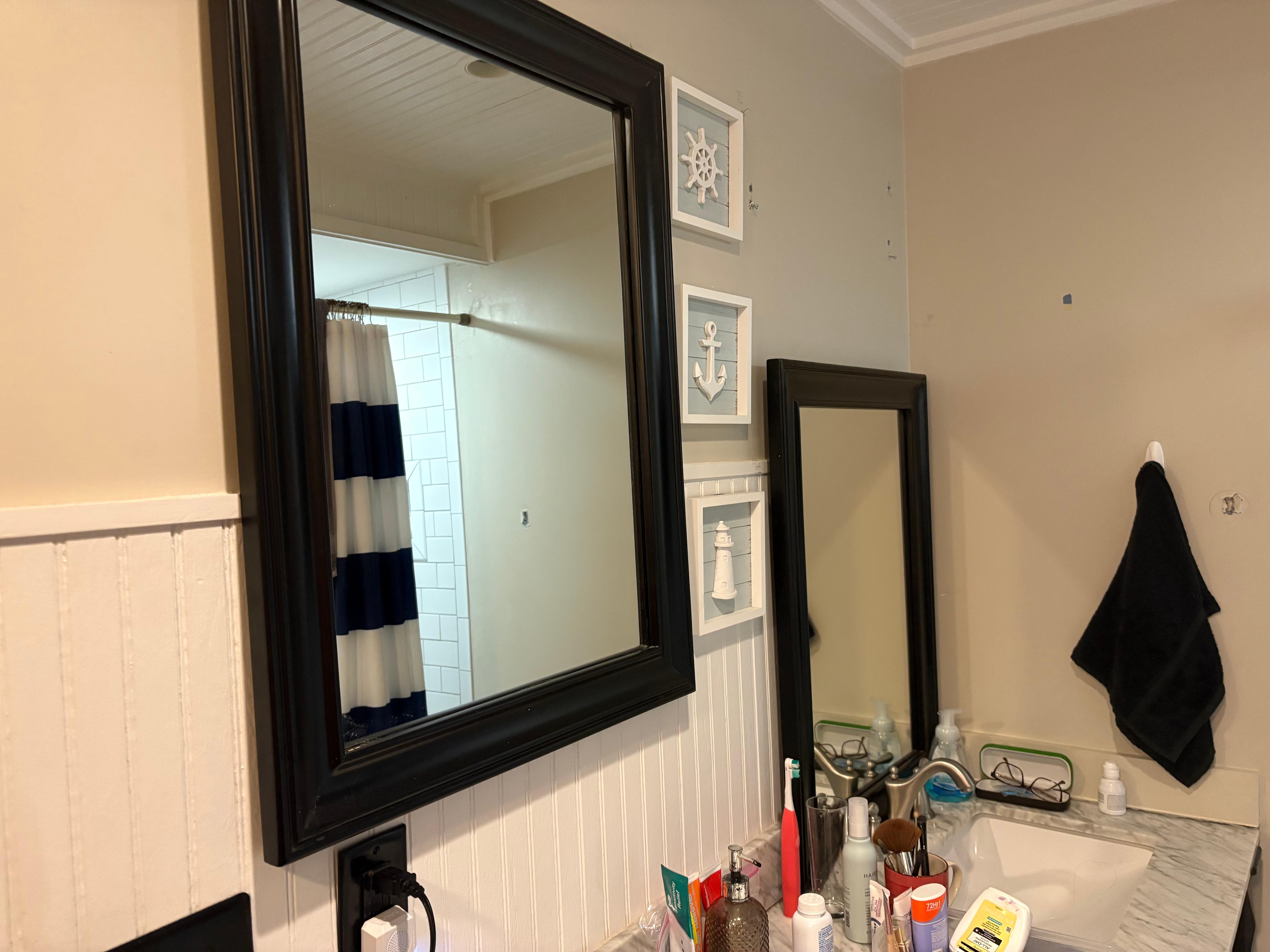 One mirror hung, the other, resting on the sink.