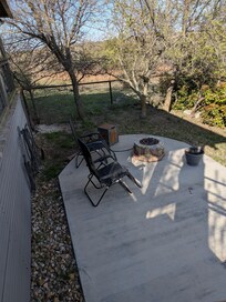 View of the patio below the deck, includes zero gravity chairs, a gas fire pit