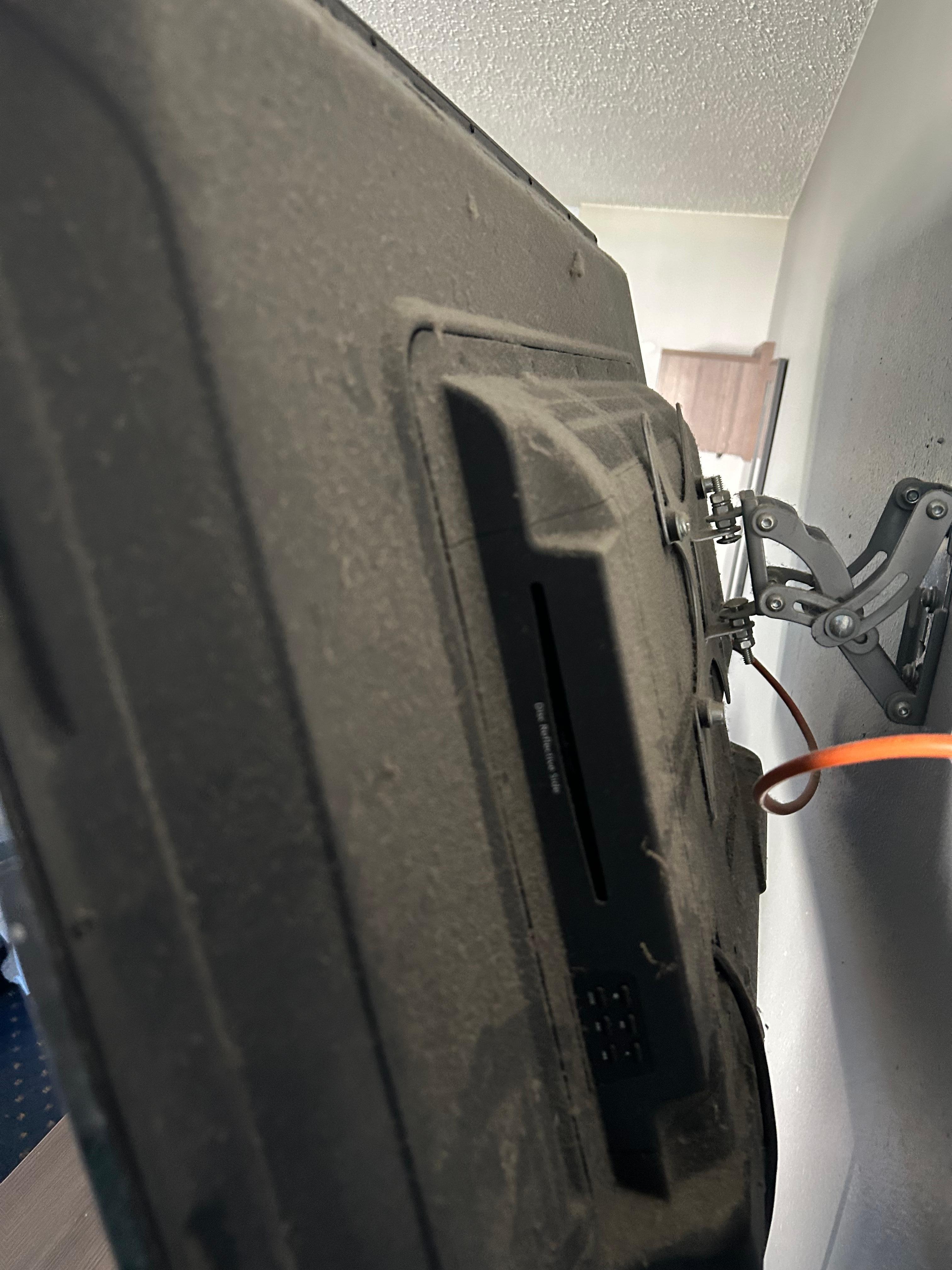 Dusty TV barely holding to the wall.