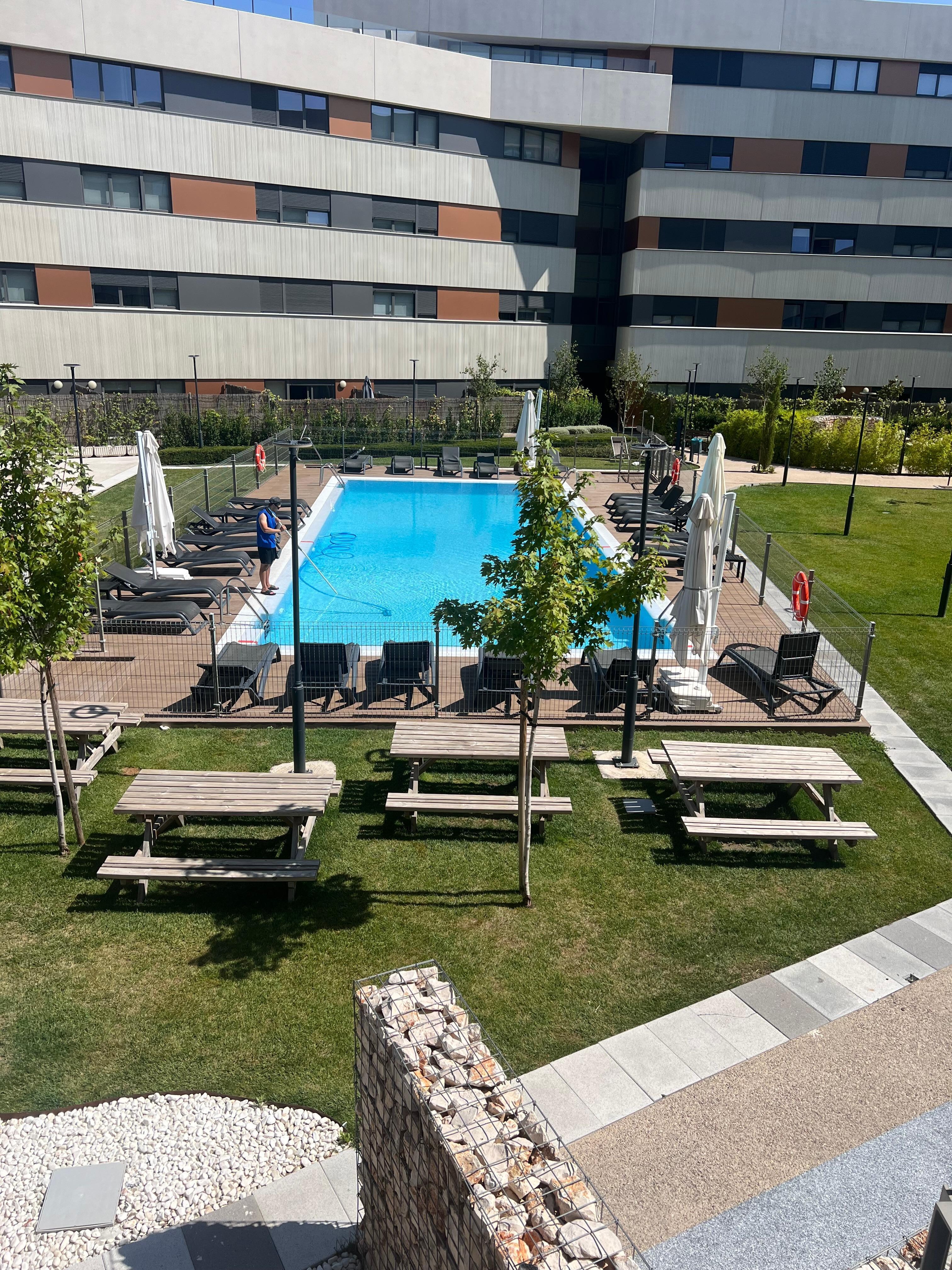 Vista general del complejo con una zona zona ajardinada con piscina 