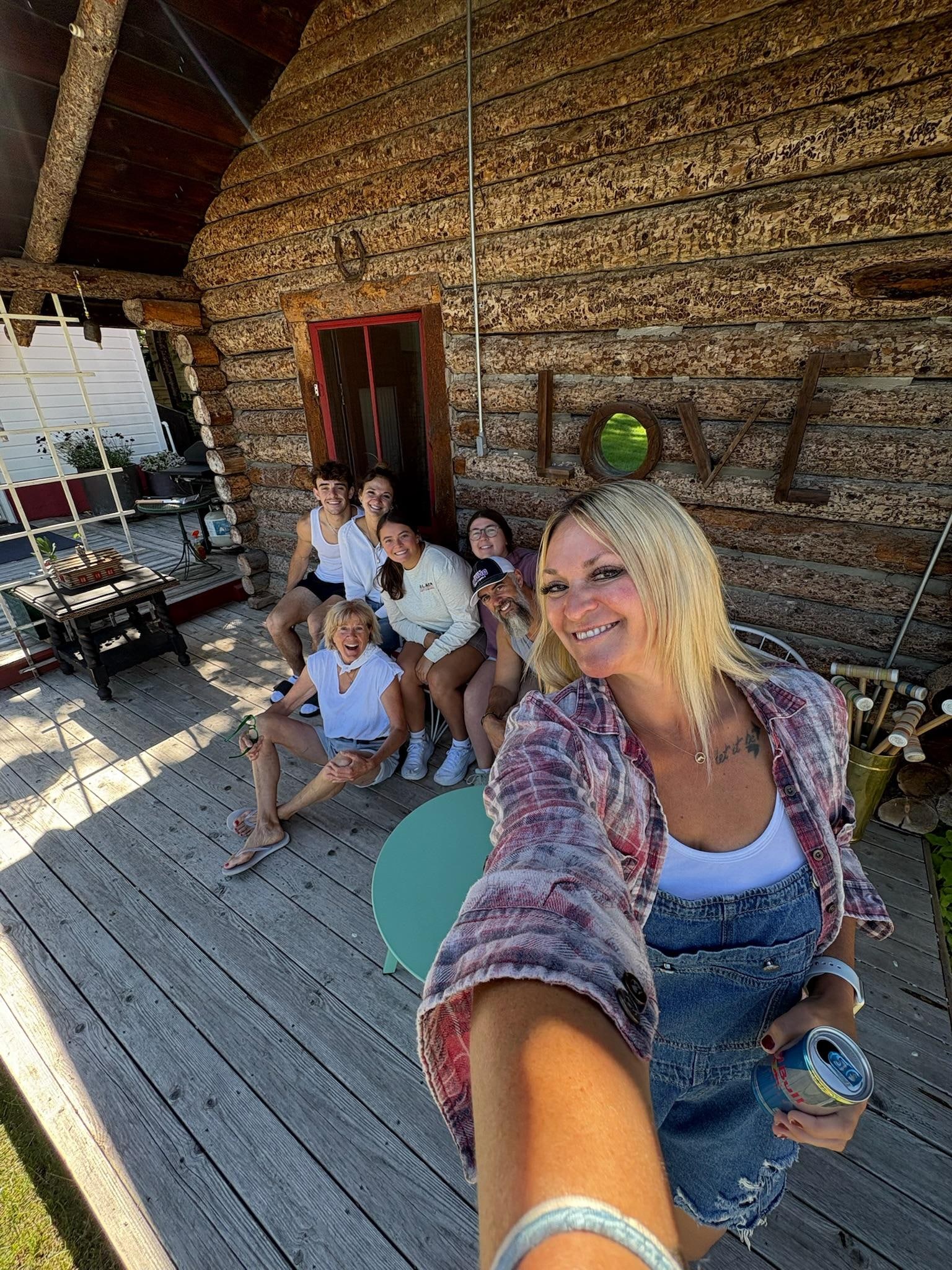Group photo in front of log cabin with our amazing host!