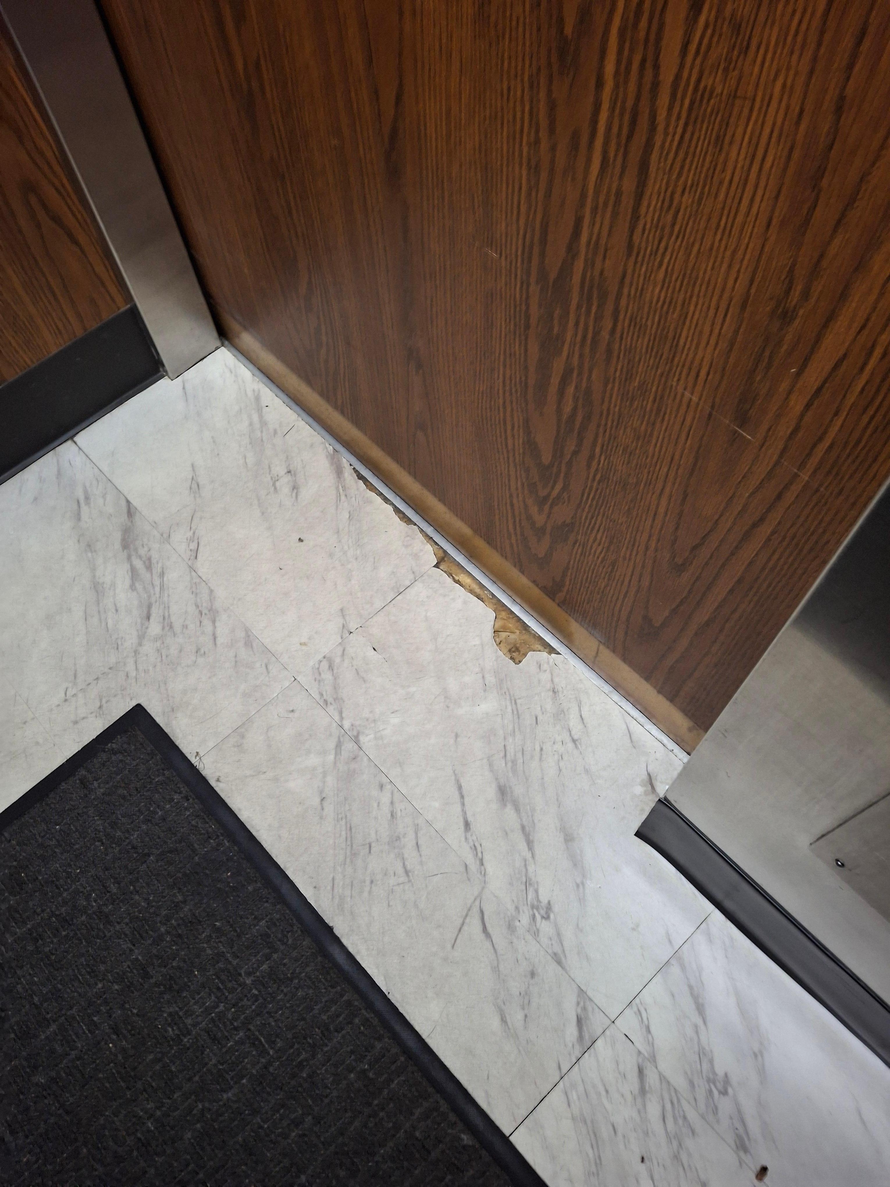 Peeling/broken tiles in the elevator.