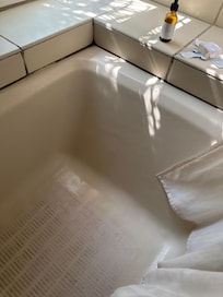 Many bits of grout in this tub are missing; likely mold growth behind the tile/tub. Tub is stained and much of the light colored grout is again dirty and seems moldy/mildew stained