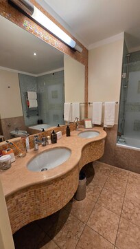 large bathroom with double sink, hairdryer and toiletries
