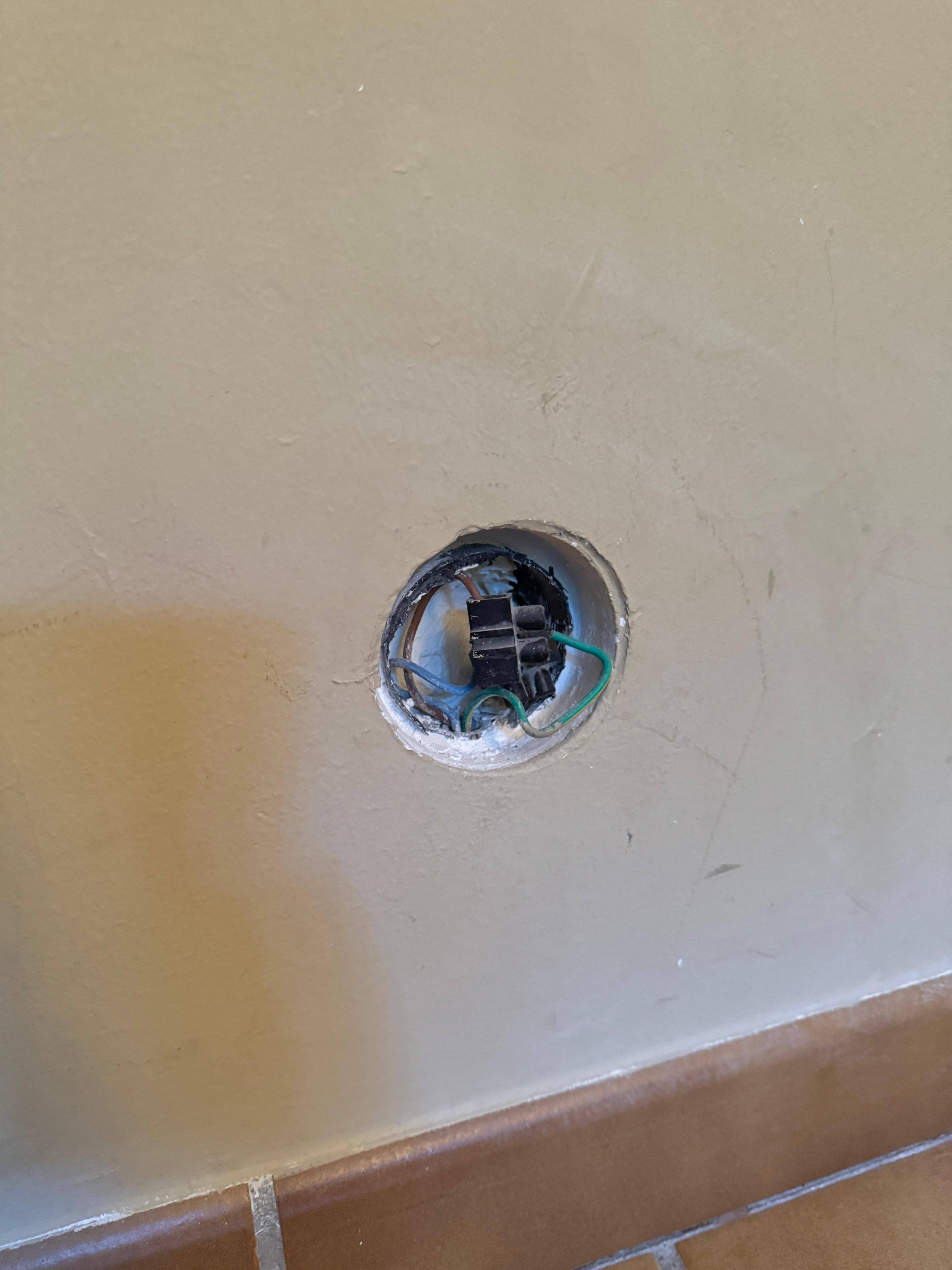 One of many holes in wall with bare wires exposed