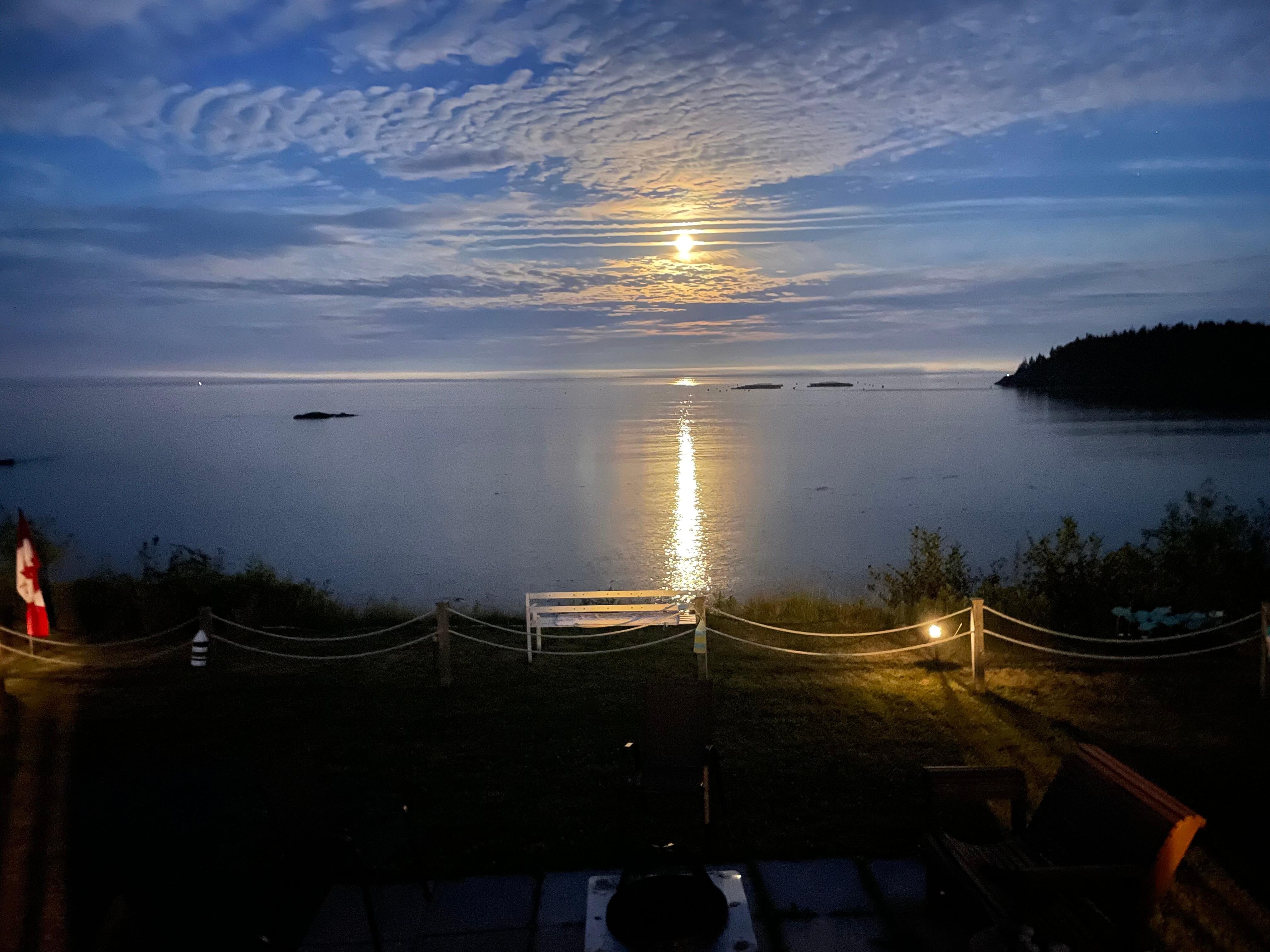 View from cottage deck. Full moon reflected on water. 