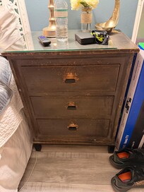 One of the two nightstands in the bedroom that is VERY scratched up - also has a random sheet of glass on the top.