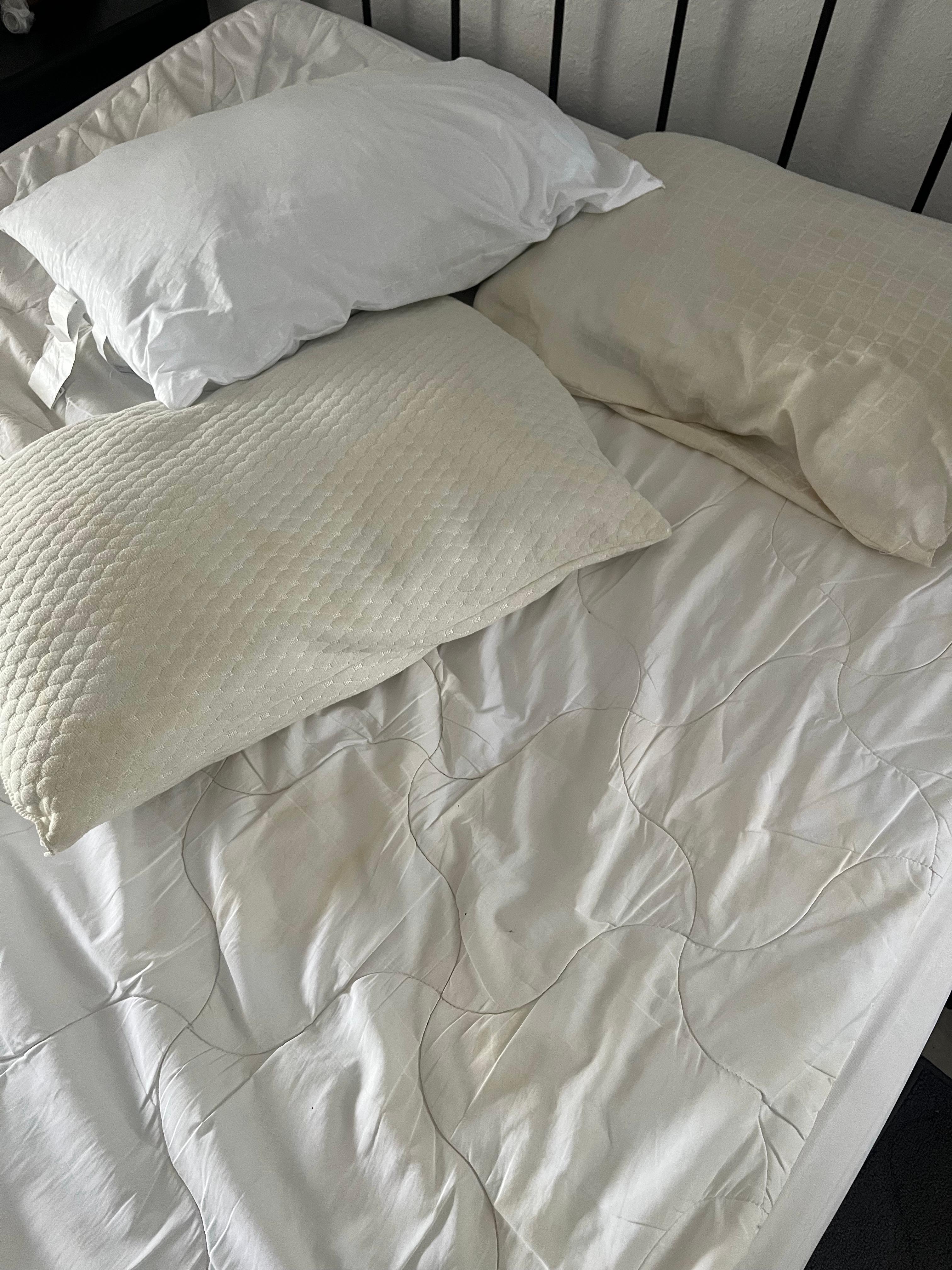 Clean pillow next to yellow pillows and mattress pad