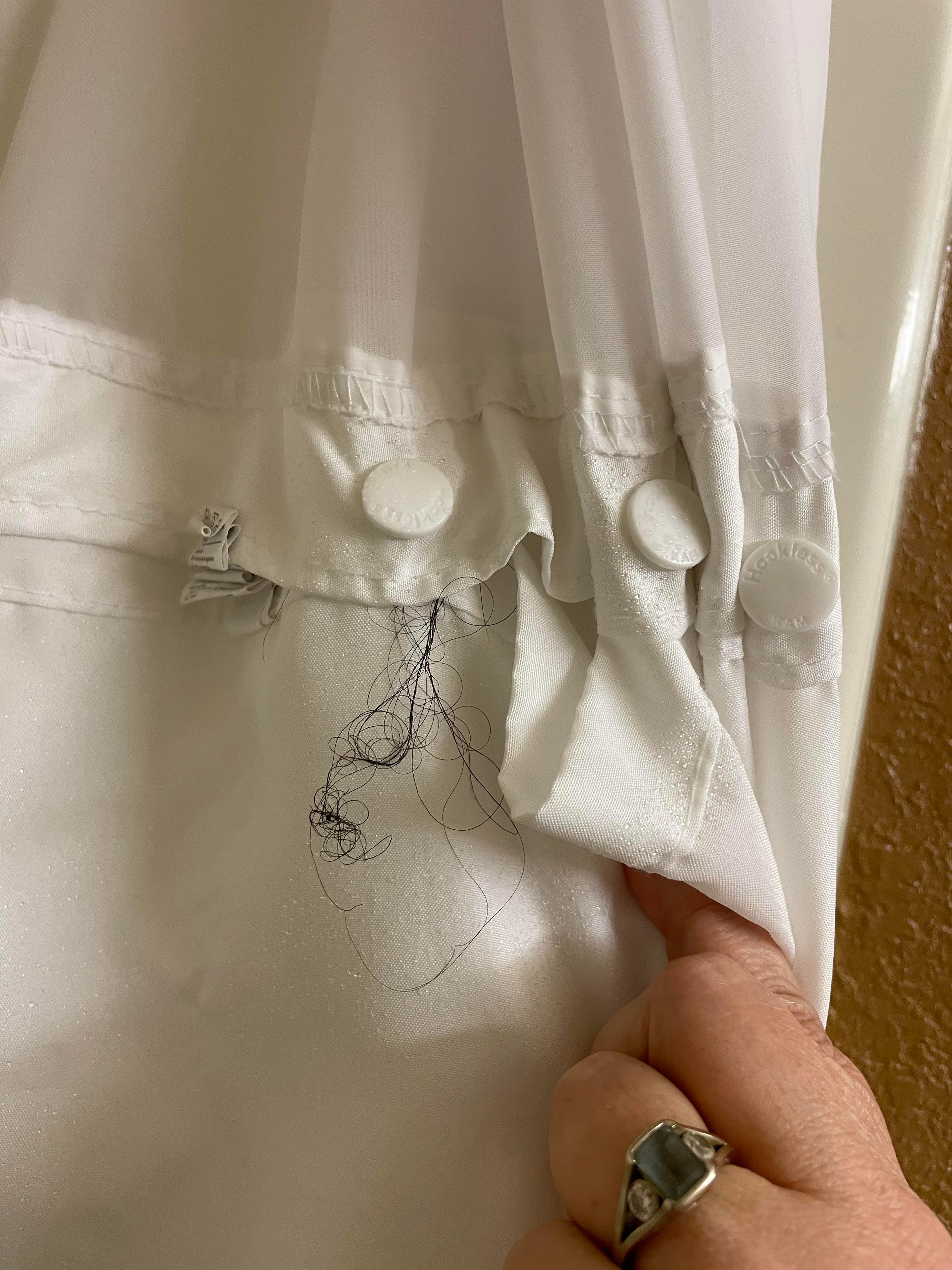 Clumps of hair hung from the shower curtain in the bathroom.