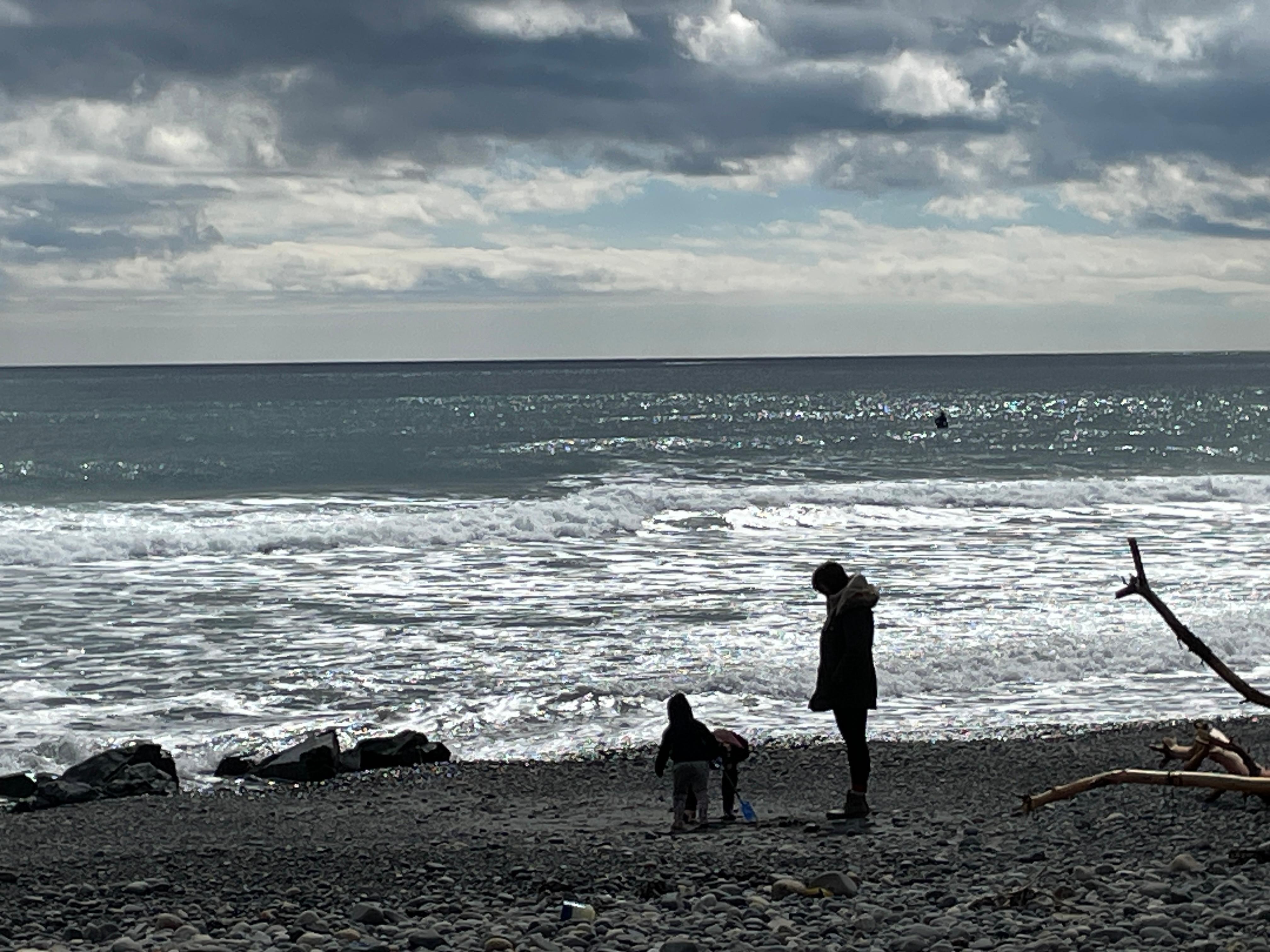 Many people/families enjoying the shore and the water (surfers)